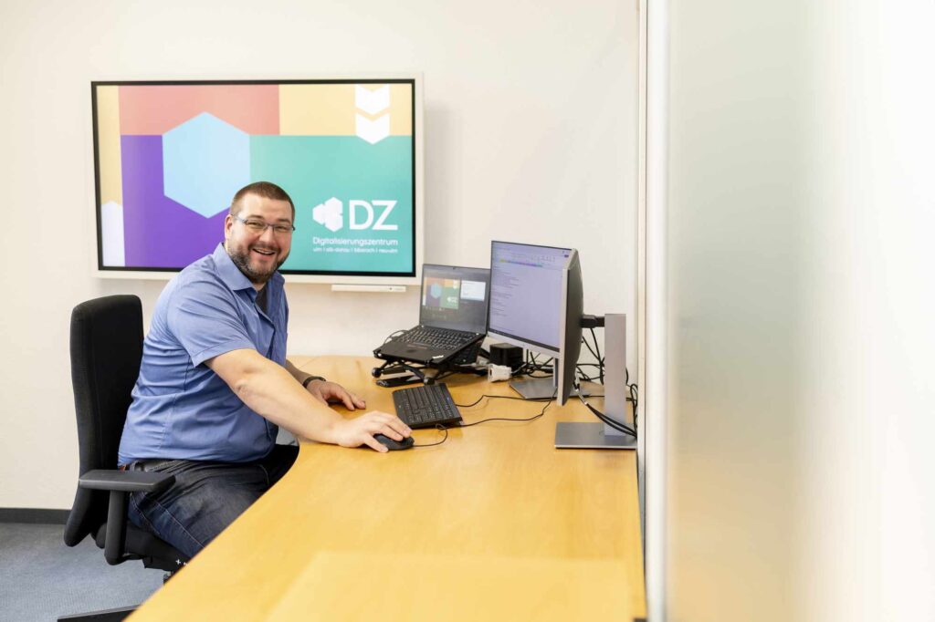 Mitarbeiter sitzt an einem Schreibtisch und arbeitet am Computer im Digitalisierungszentrum.