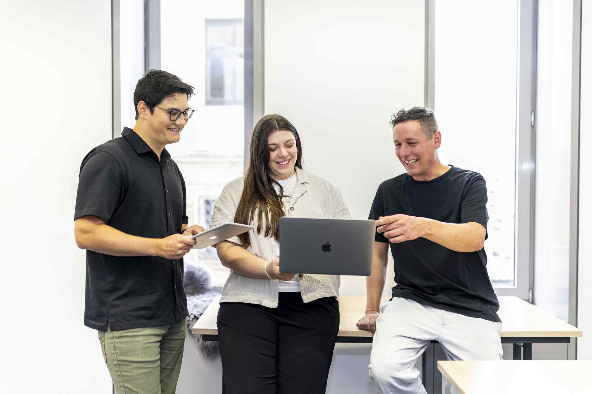 Drei Personen arbeiten gemeinsam im Digitalisierungszentrum mit einem Laptop.