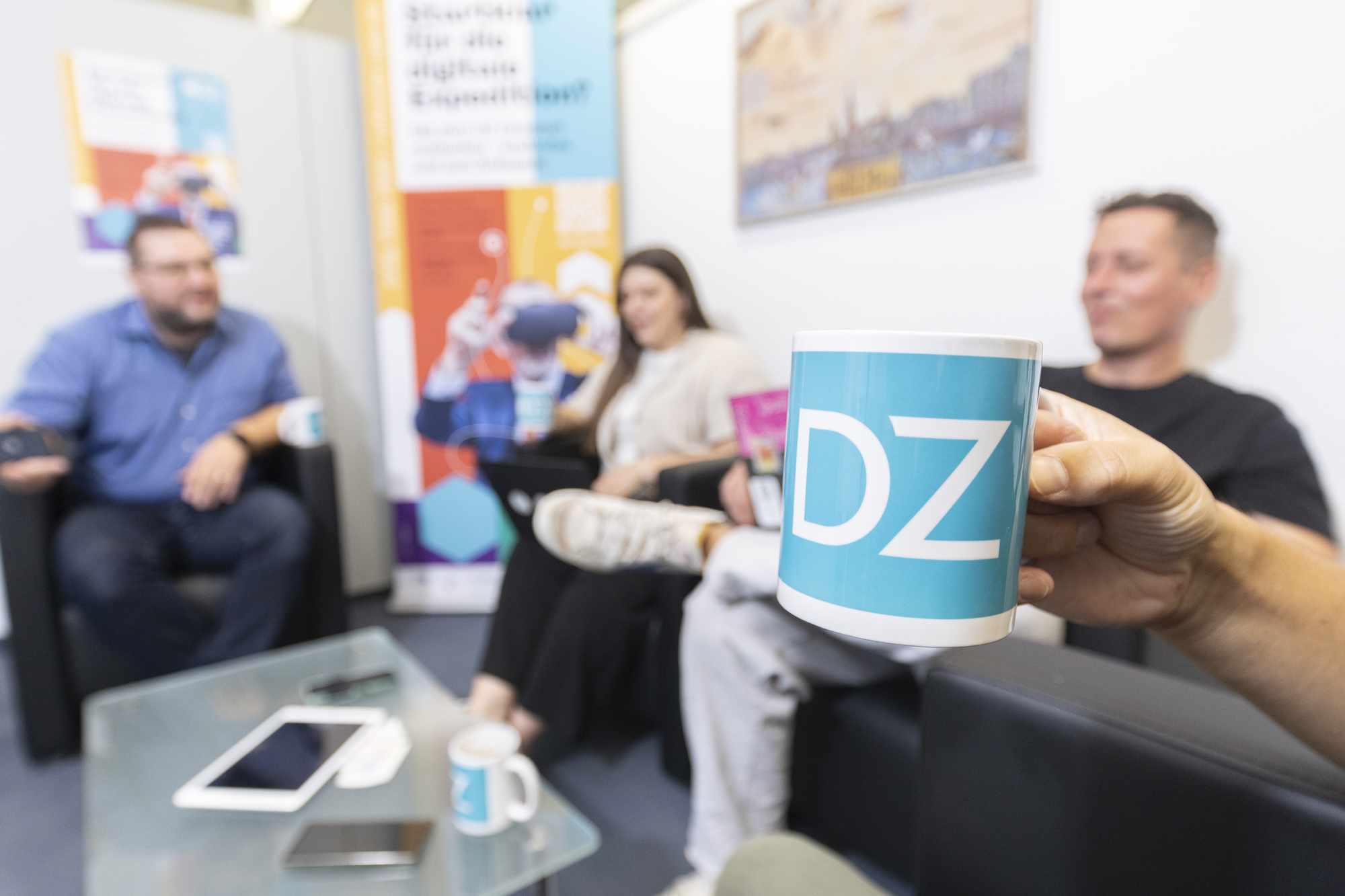 Personen beim Gespraech im Digitalisierungszentrum Ulm mit einer Tasse im Vordergrund