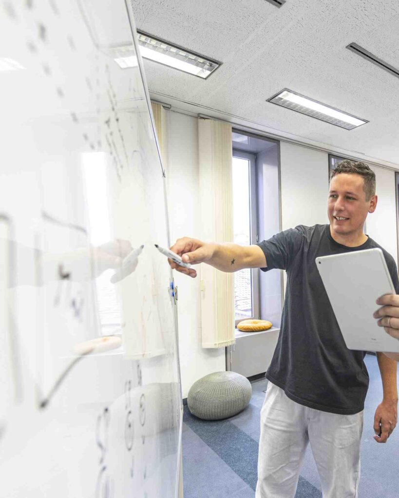 Person erklaert an einem Whiteboard in einem modernen Seminarraum.