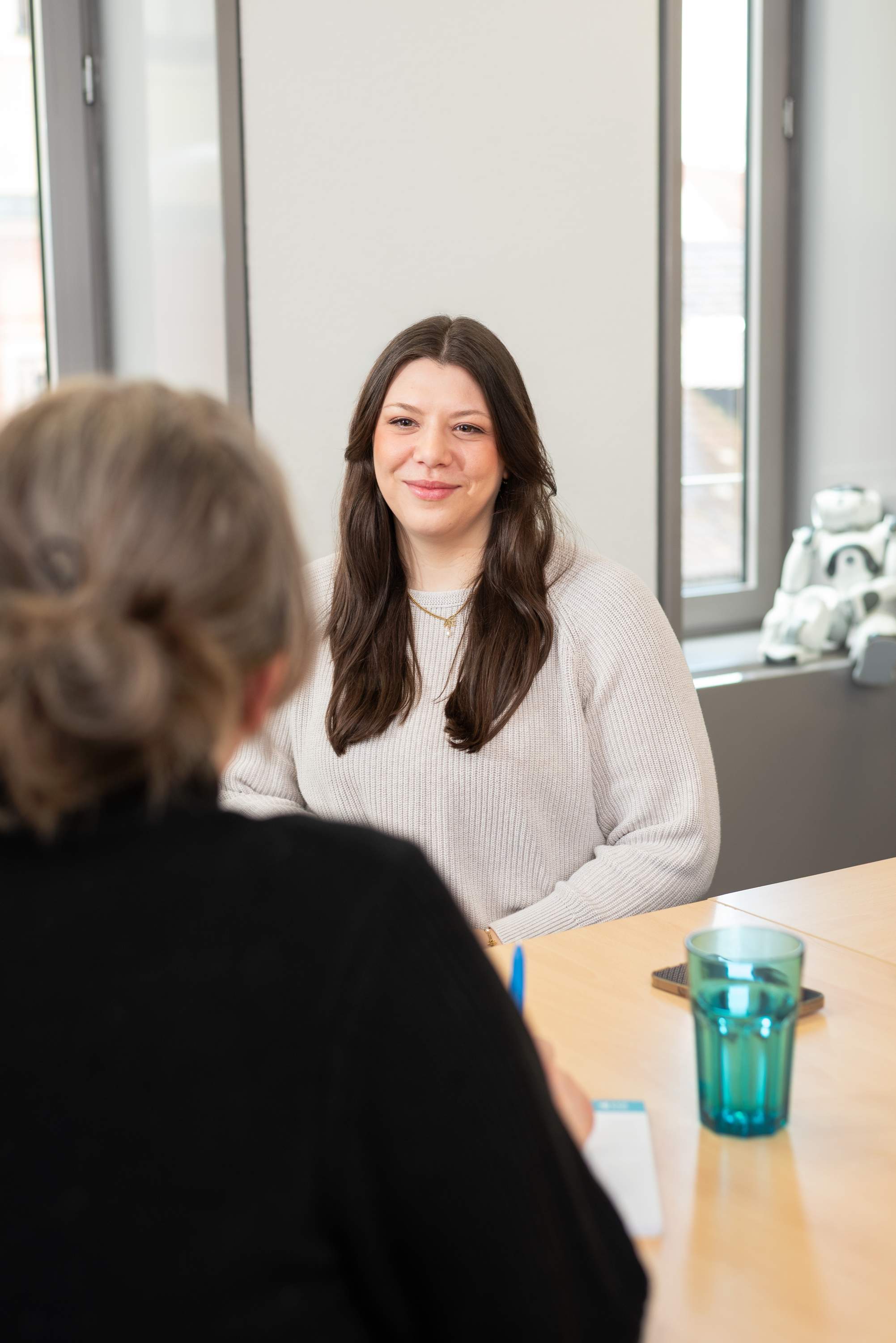 Eine Frau im Beratungsgespräch lächelt in die Kamera.