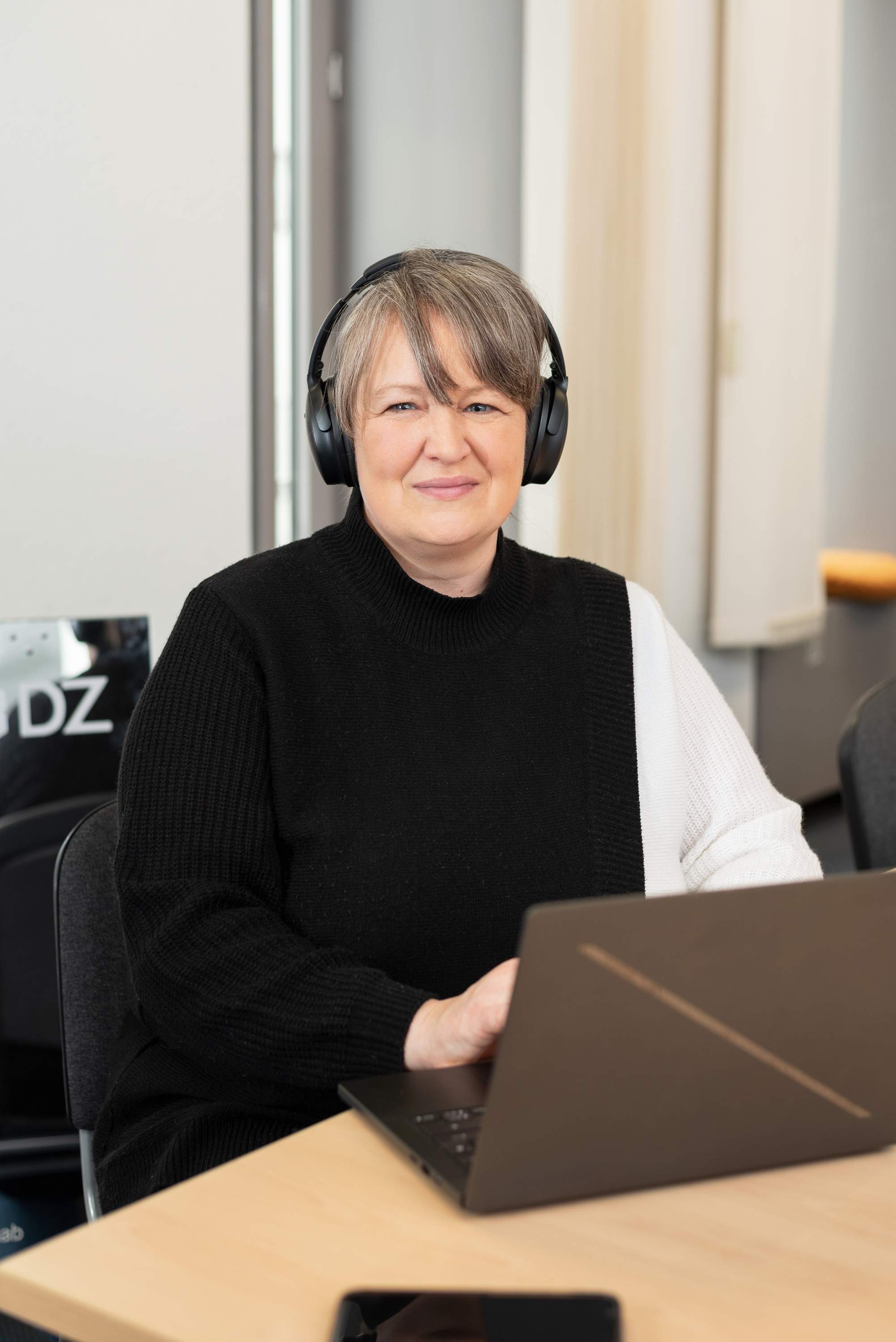 Eine Frau mit Headset lächelt in die Kamera.