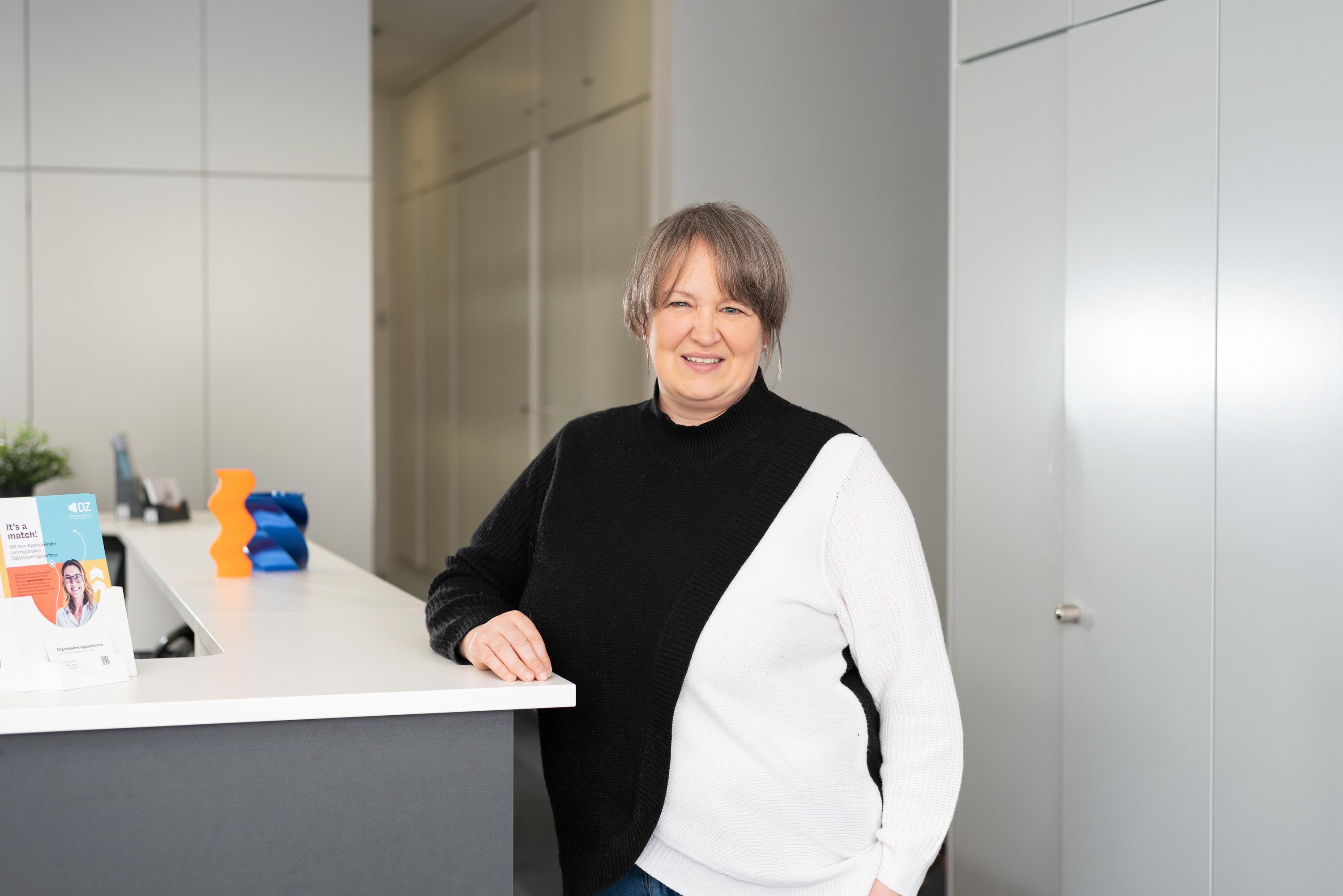 Katja Feicht steht am Empfang eines modernen Bueros im Digitalisierungszentrum Ulm Alb-Donau Biberach Neu-Ulm.