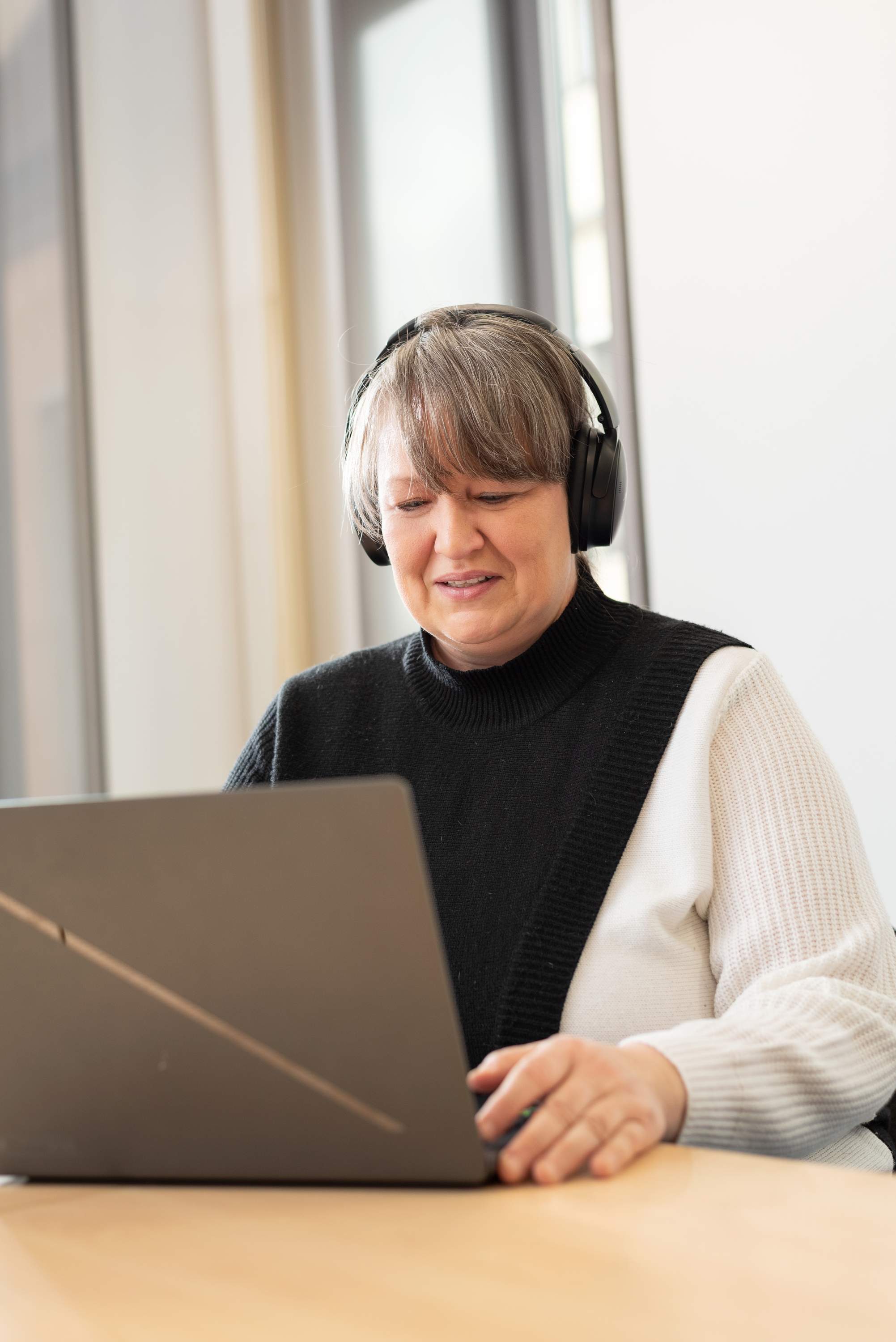 Eine Frau mit einem Headset sitzt vor einem Notebook.