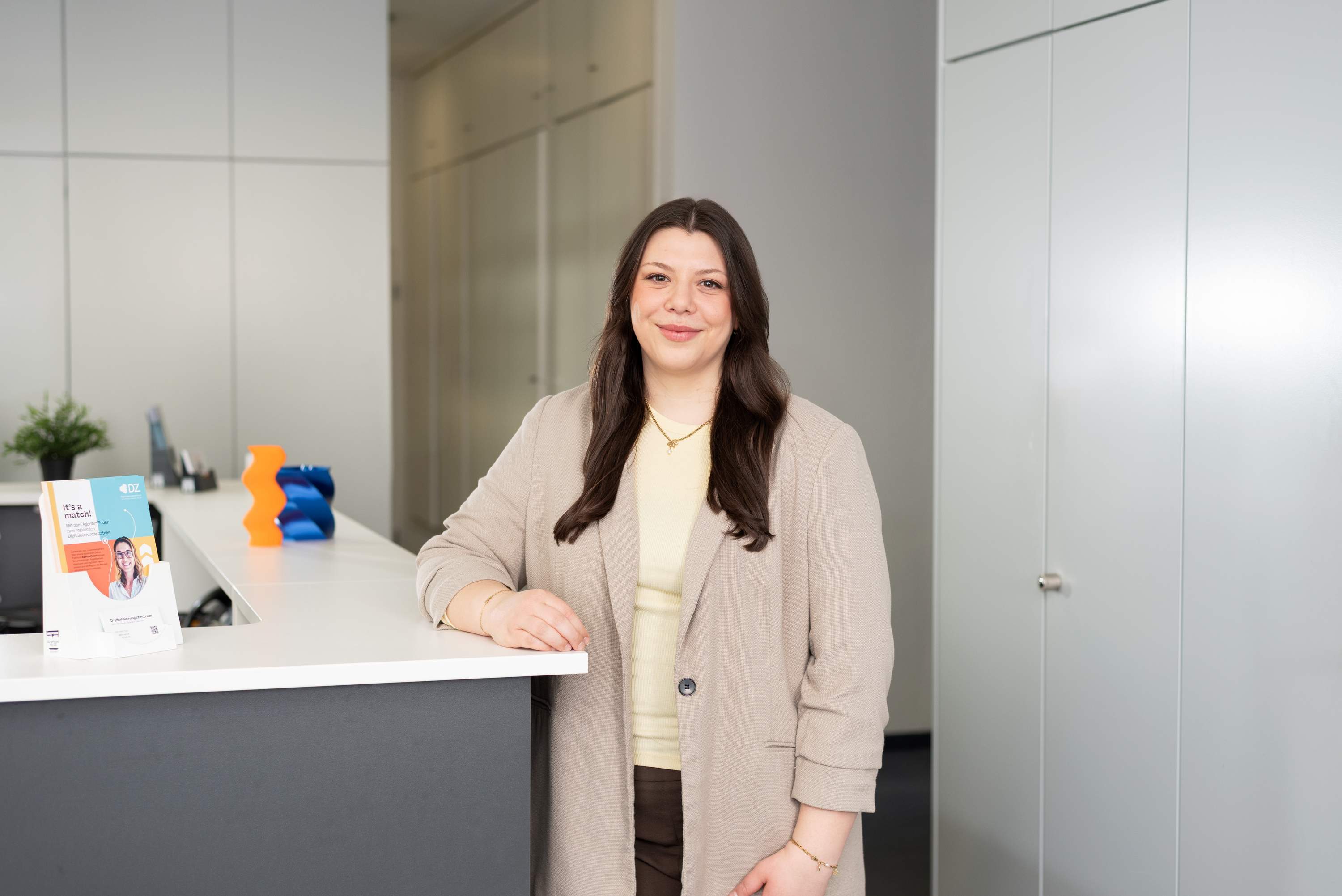 Vanessa Sclafani steht am Empfang eines modernen Bueros im Digitalisierungszentrum Ulm Alb-Donau Biberach Neu-Ulm.