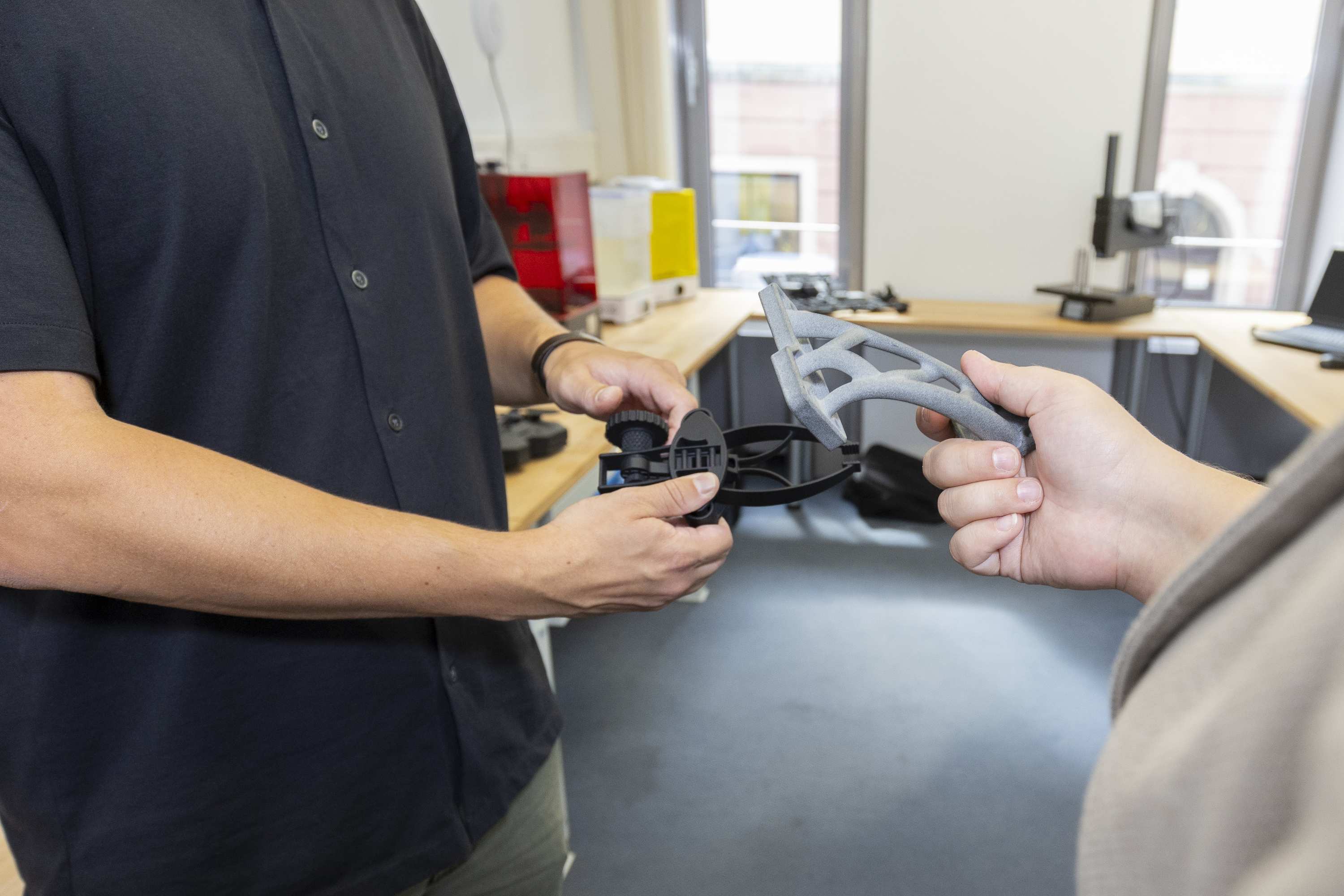 Detailbild: Personen halten 3D-gedruckte Teile in der Hand.