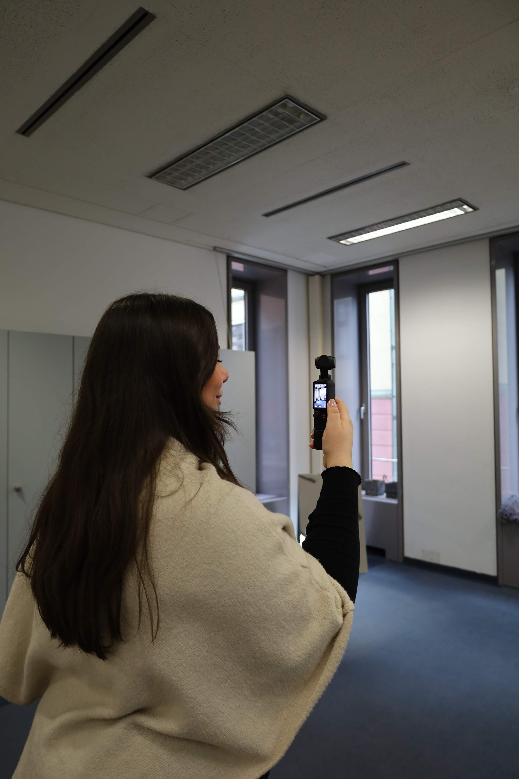 Frau filmt mit einer 360 Grad Kamera den Raum.