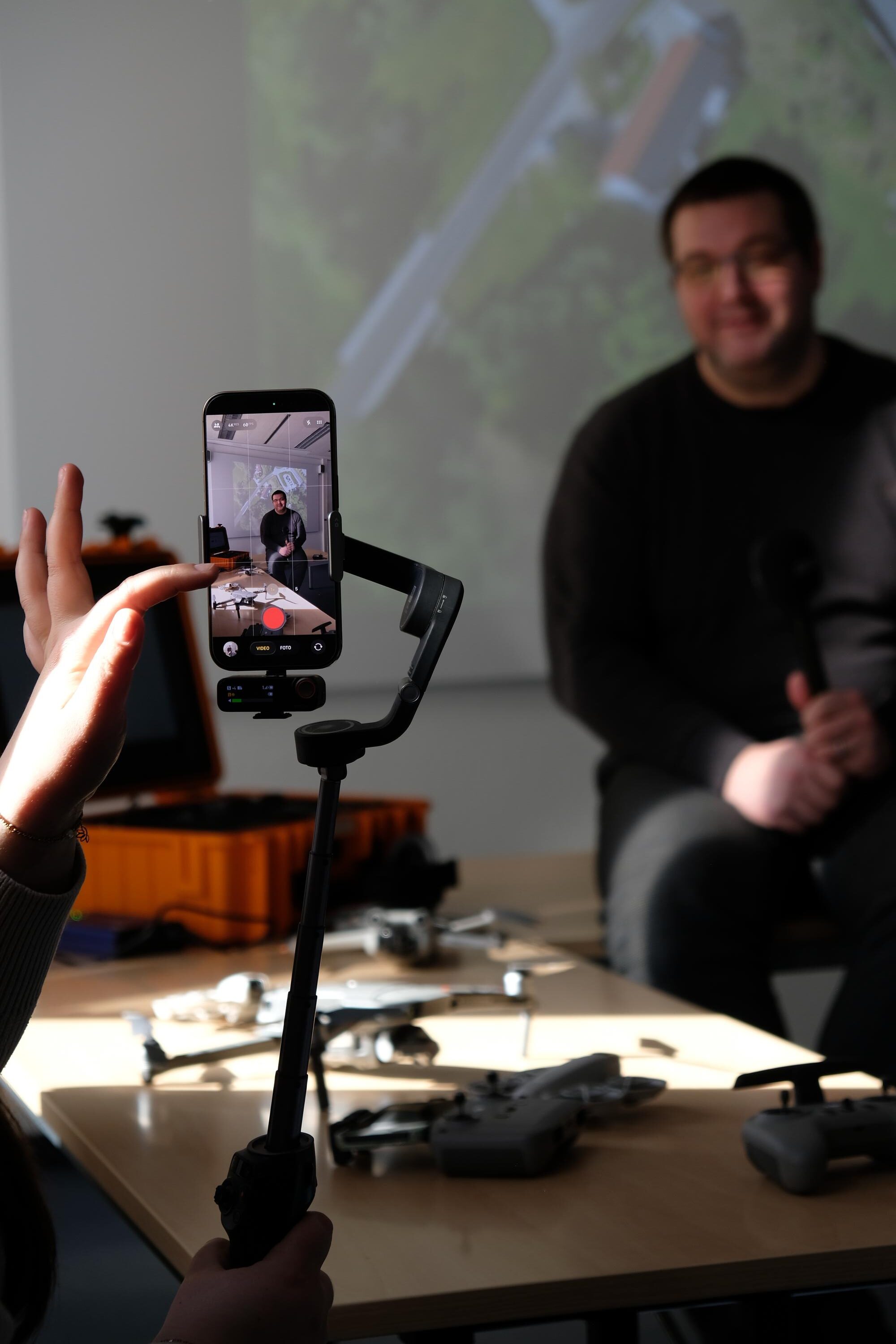 Person wird bei einem Interview im Digitalisierungszentrum mit einem Smartphone gefilmt