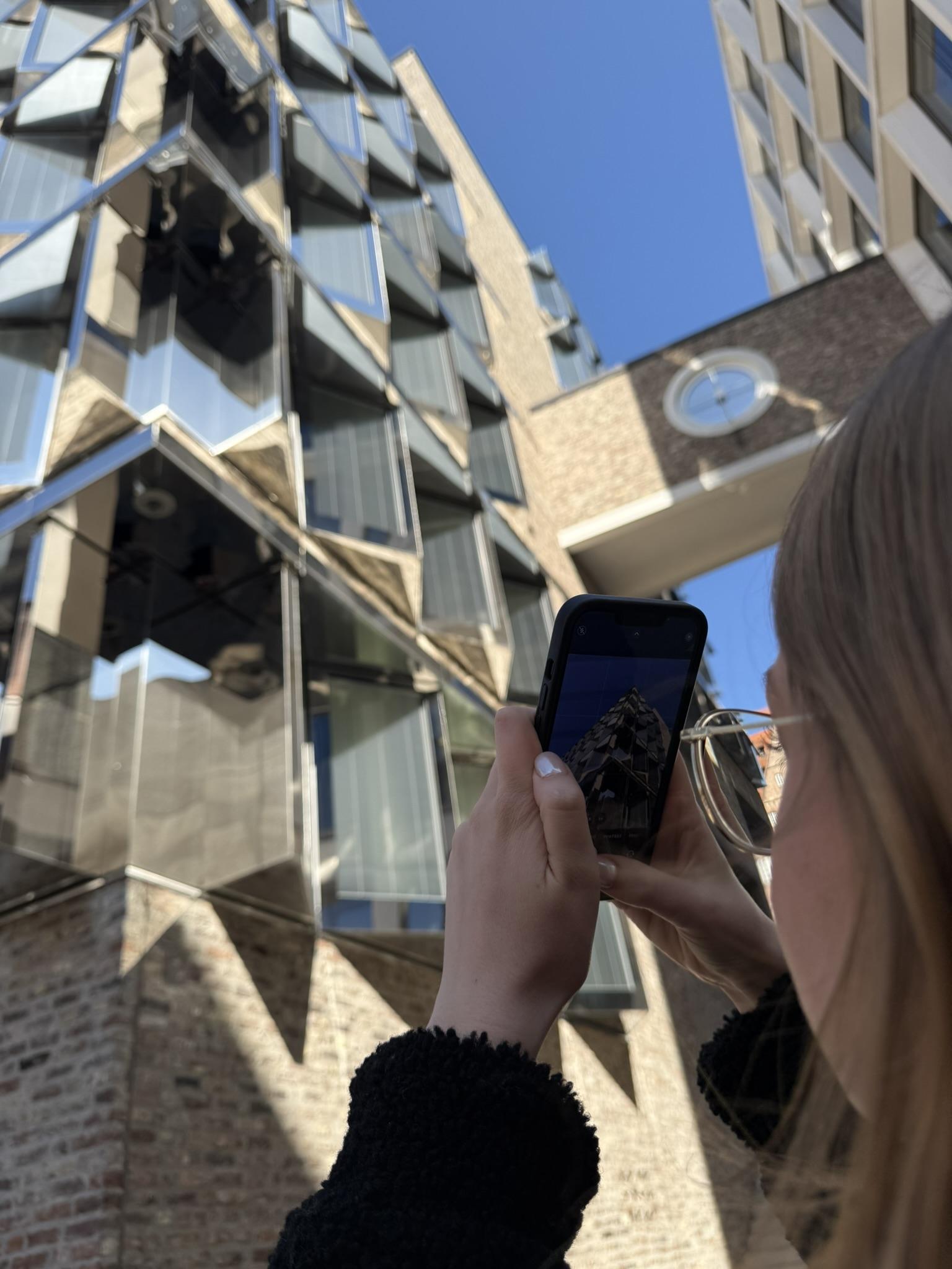 Frau fotografiert mit einem Smartphone ein Gebäude.