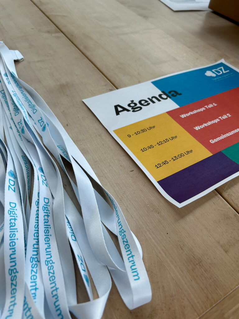 Agenda der Anwendertage Digitalisierung liegt neben Namensbaendern des Digitalisierungszentrums auf einem Tisch.