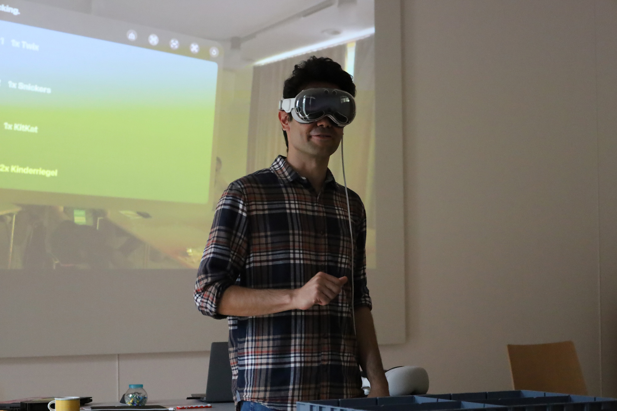 Person mit Mixed Reality Brille steht vor einer projizierten Anwendung in einem Raum.