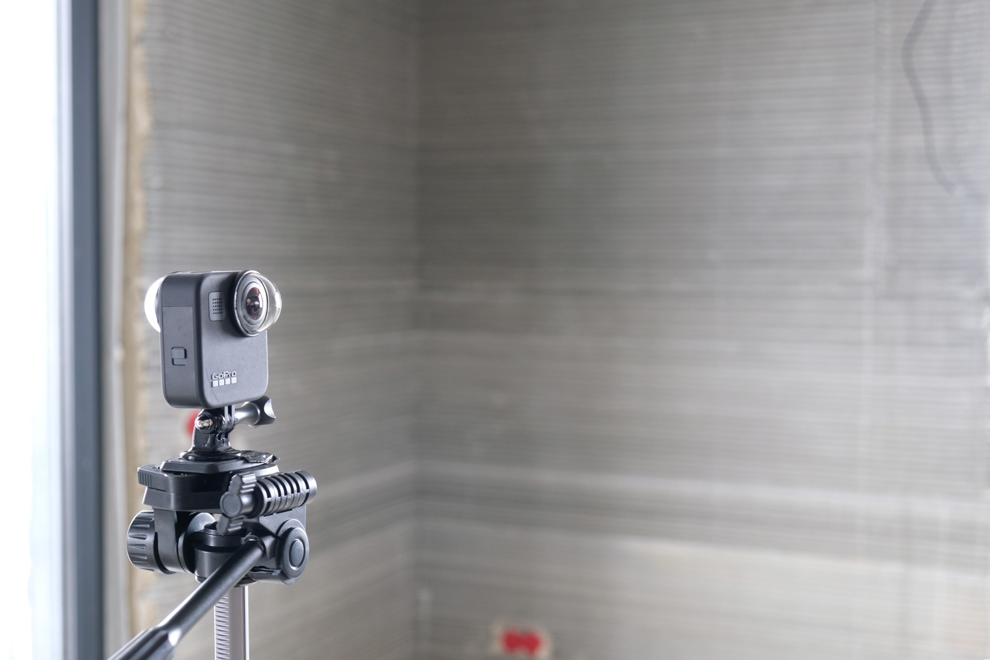 GoPro Kamera auf einem Stativ vor einer grauen Wand.