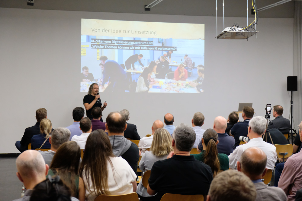 Ein Referent spricht vor einem sitzenden Publikum ueber die Umsetzung von KI Themen im Digitalisierungszentrum Ulm.