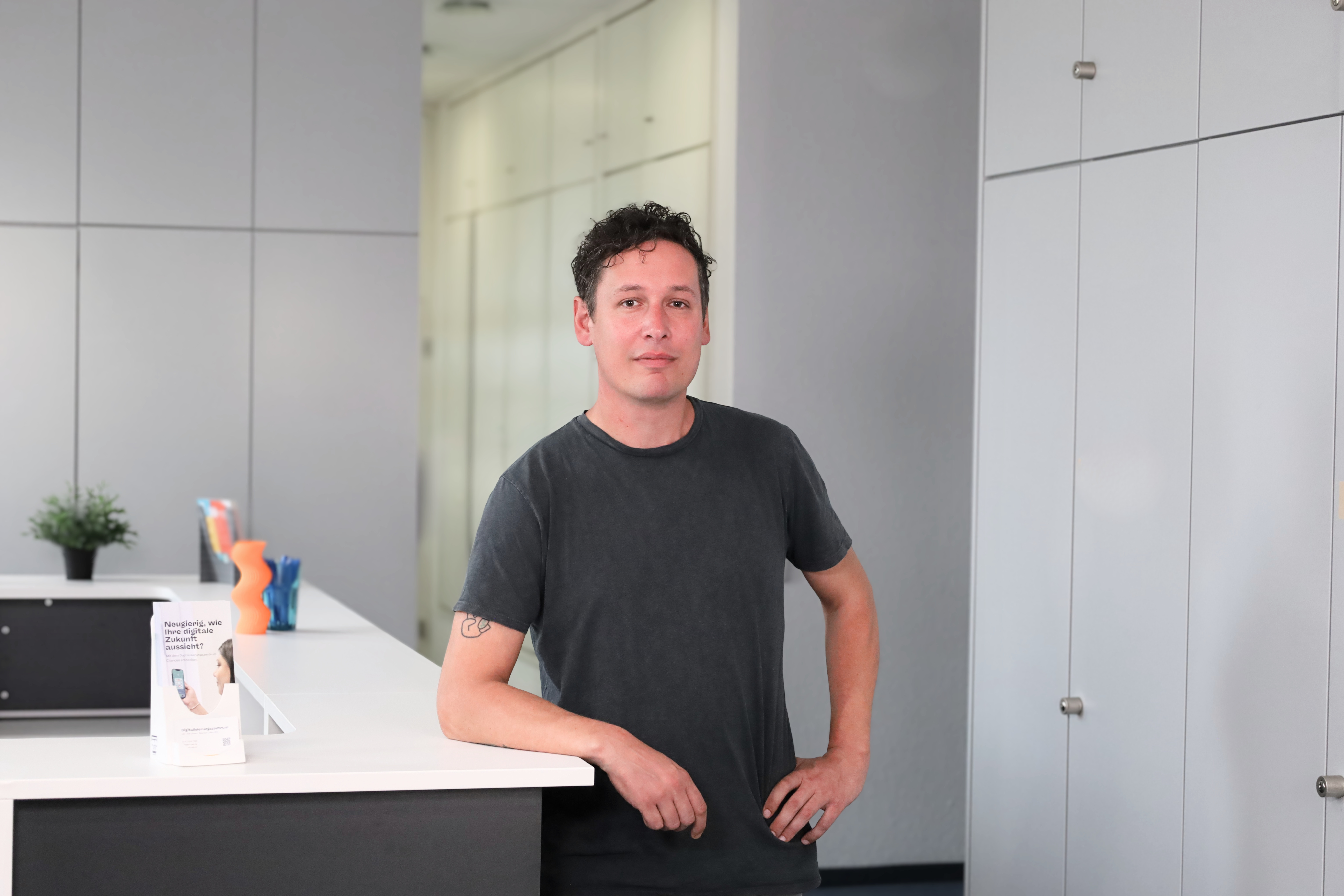 Jan Schaefer steht am Empfang eines modernen Bueros im Digitalisierungszentrum Ulm Alb-Donau Biberach Neu-Ulm.