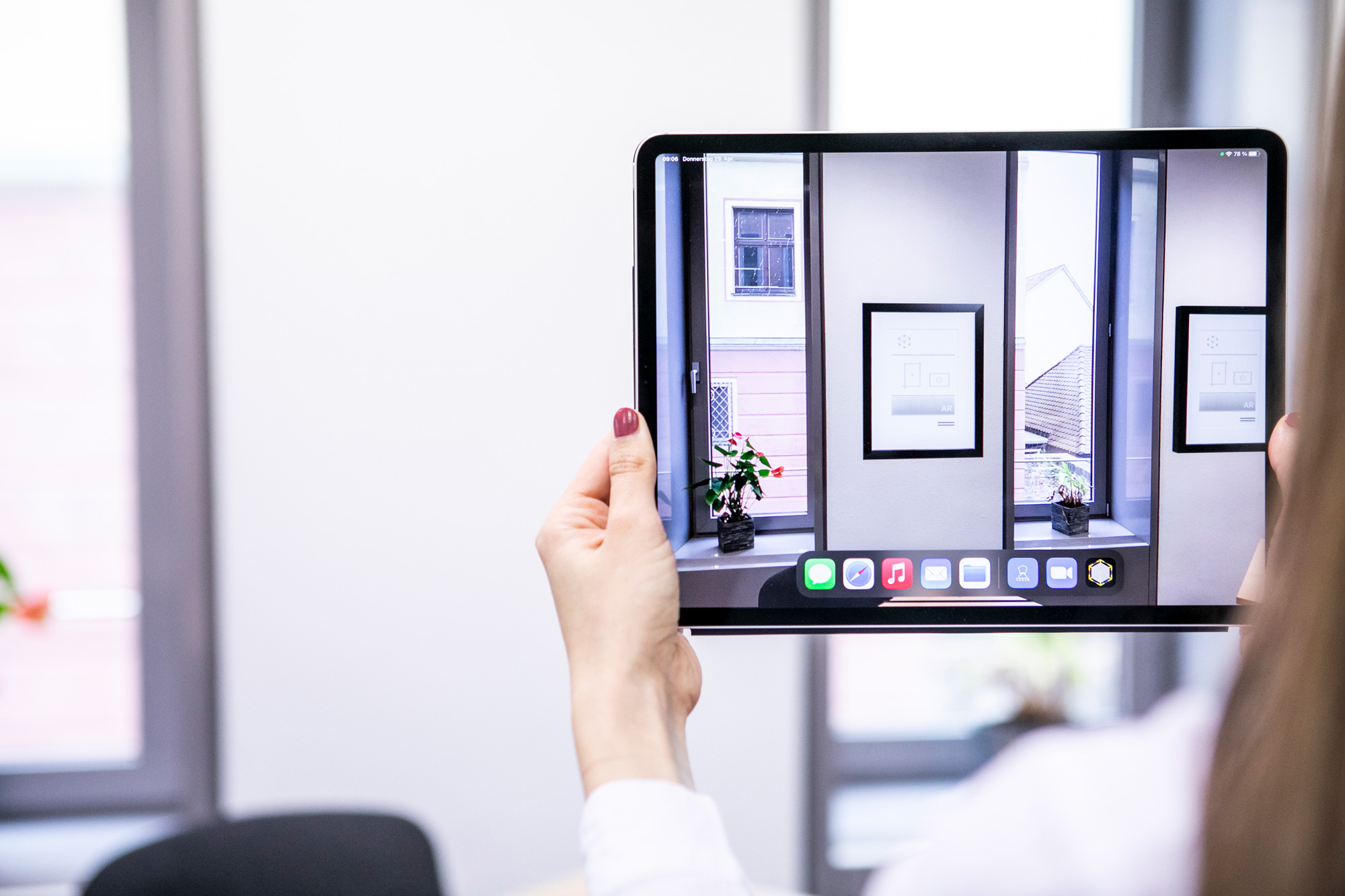 Person haelt ein Tablet vor ein Fenster, auf dessen Bildschirm eine Augmented Reality Anwendung zu sehen ist.