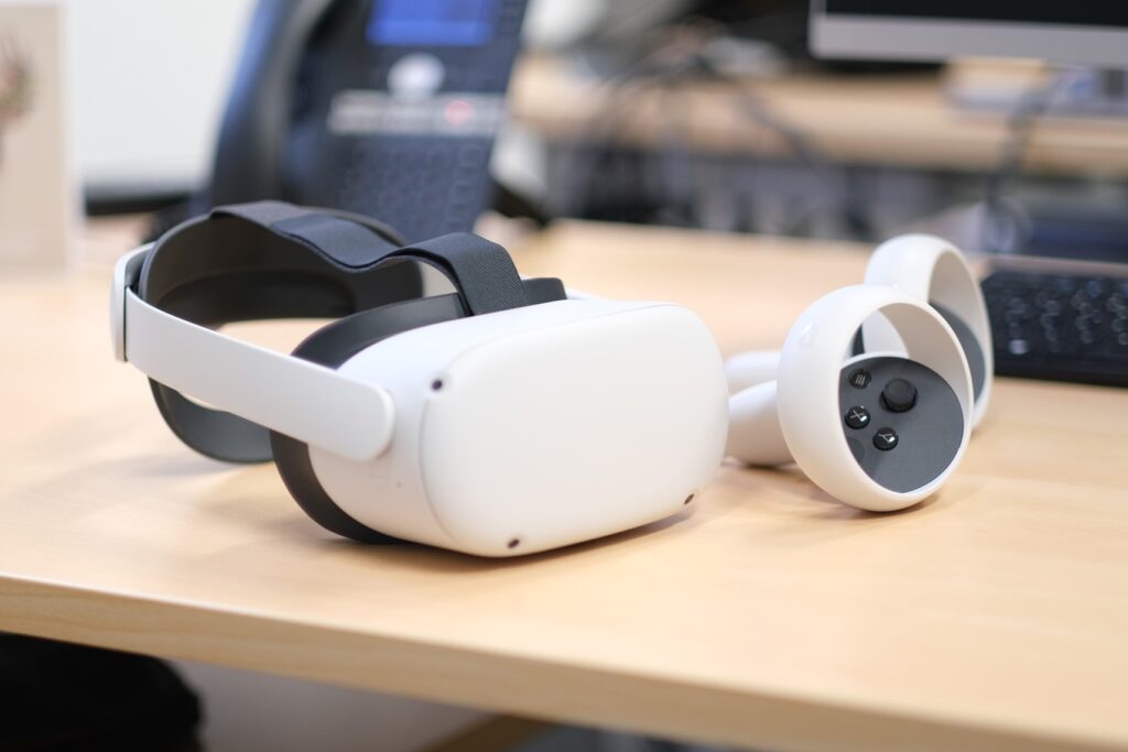 Weisse VR Brille mit zwei Controllern liegt auf einem hellen Holztisch.